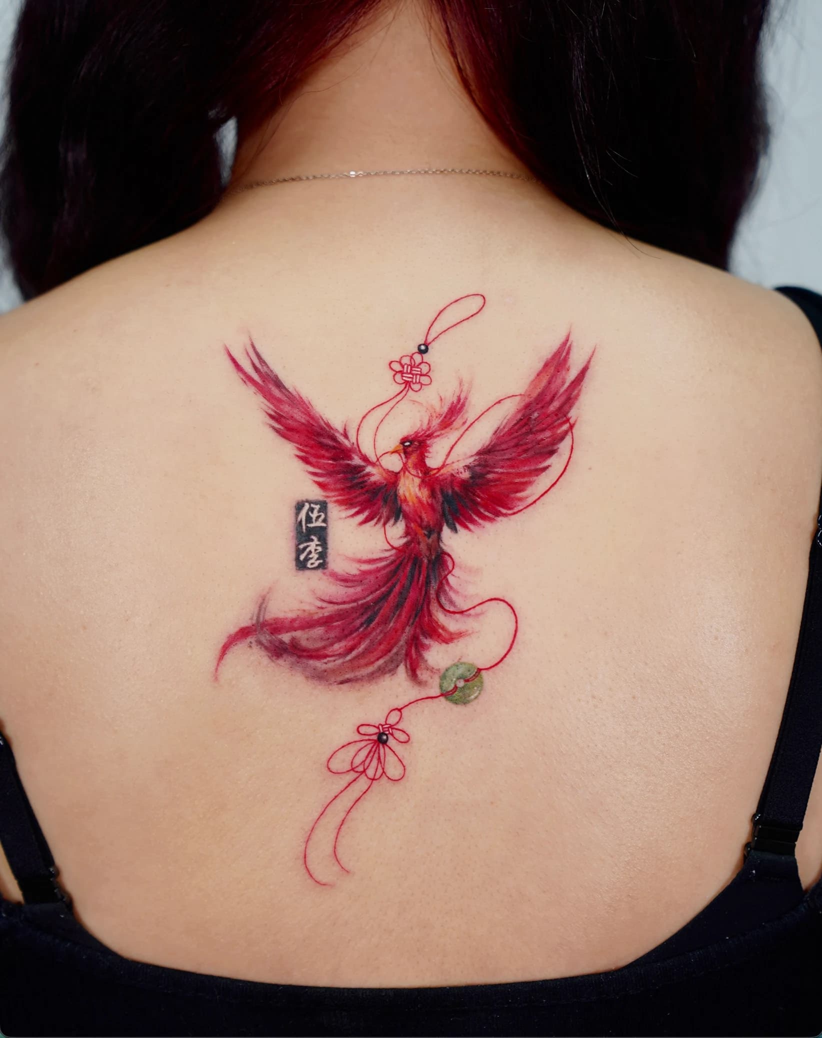 Red phoenix back tattoo with a Chinese tassel and green jade charm