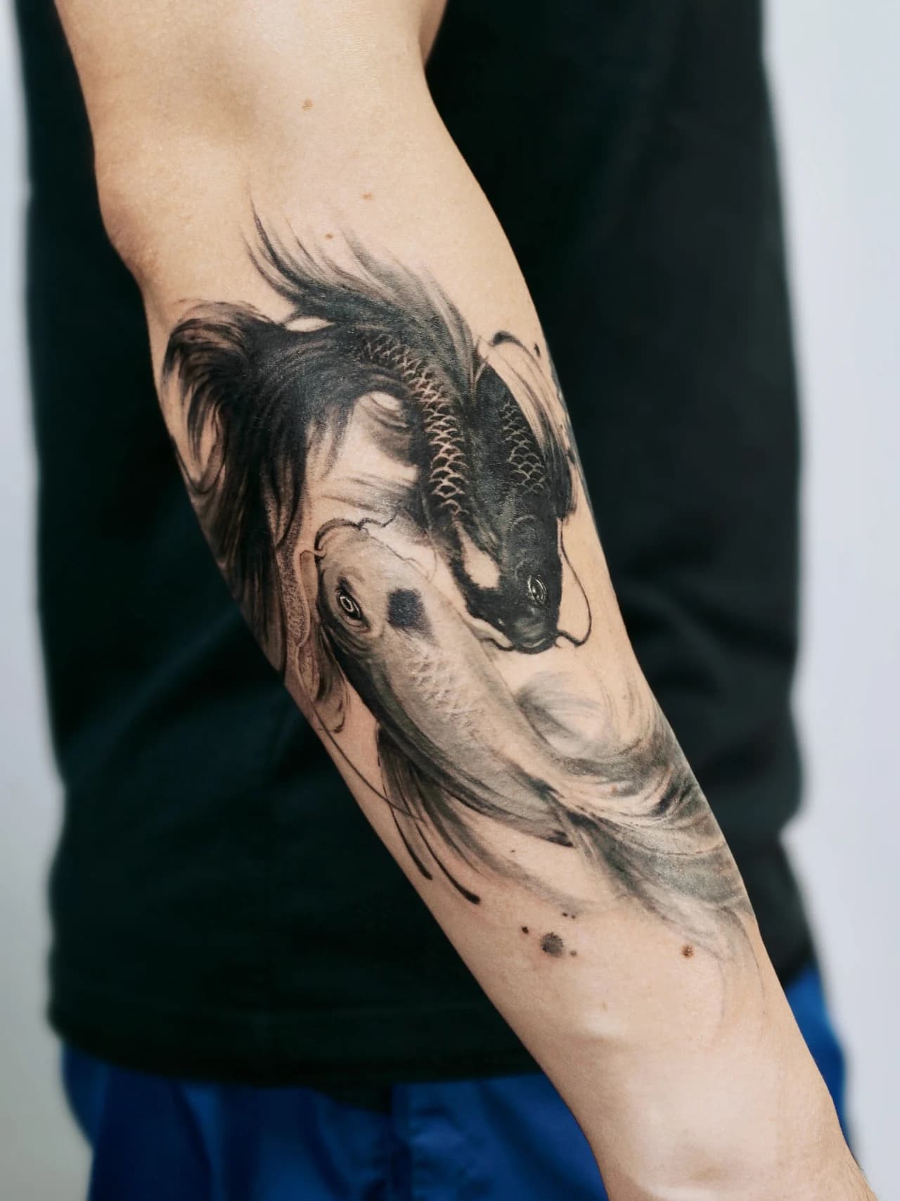 Neo-traditional Chinese ink koi tattoo forming a yin-yang symbol on the forearm